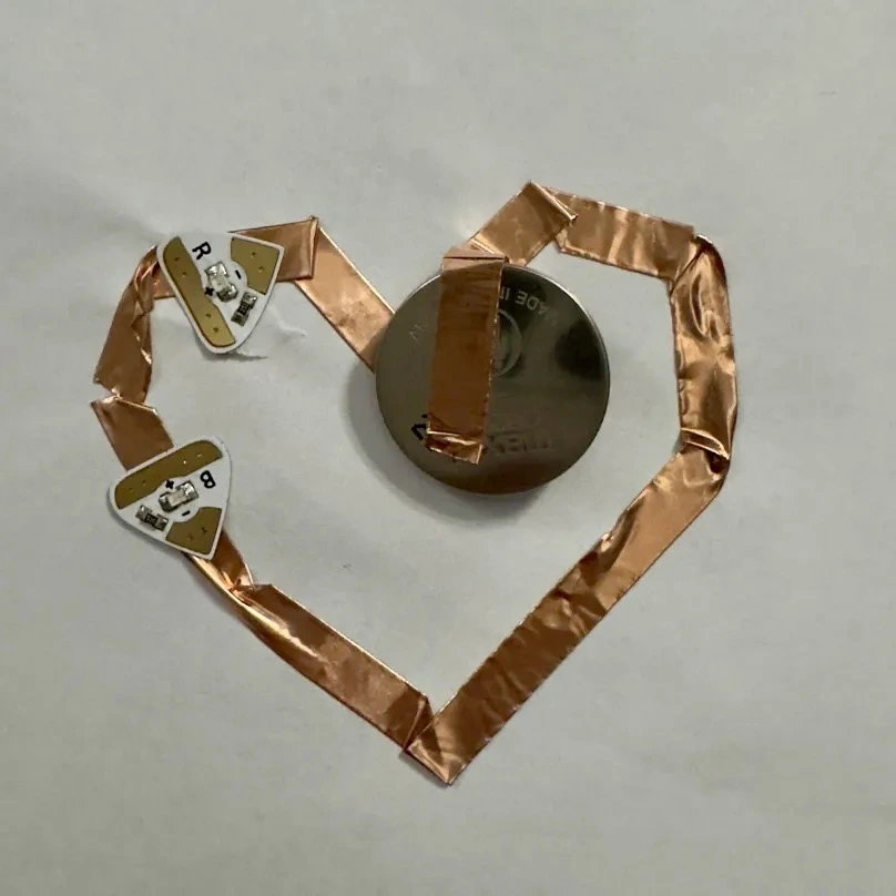 I decided to test it out with just a few lights on the heart so as to avoid wasting the LED stickers without knowing if I'm even doing it right. It didn't work. I figured this one didn't work because the negative side of the LED was facing towards the positive side of the battery. Also, I placed the LED on top of the tape instead of breaking the tape around the light, which messed the circuit up.